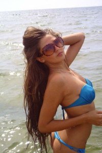Красивая брюнетка в голубом купальнике и в солнечных очках в море брюнетка в голубом купальнике